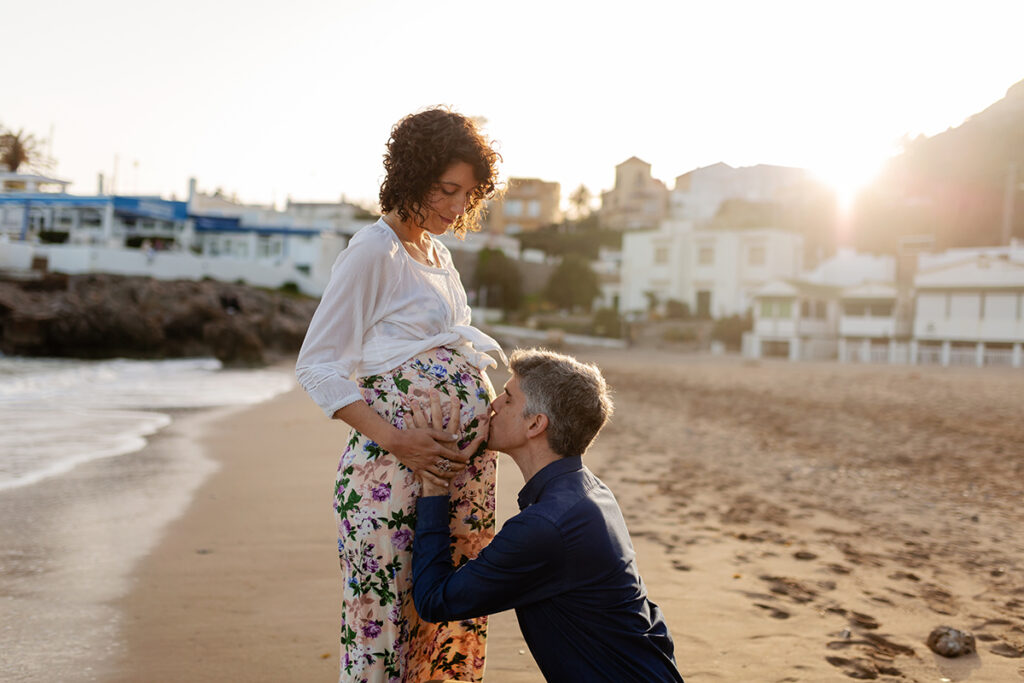 Pareja embarazada en la playa al atardecer