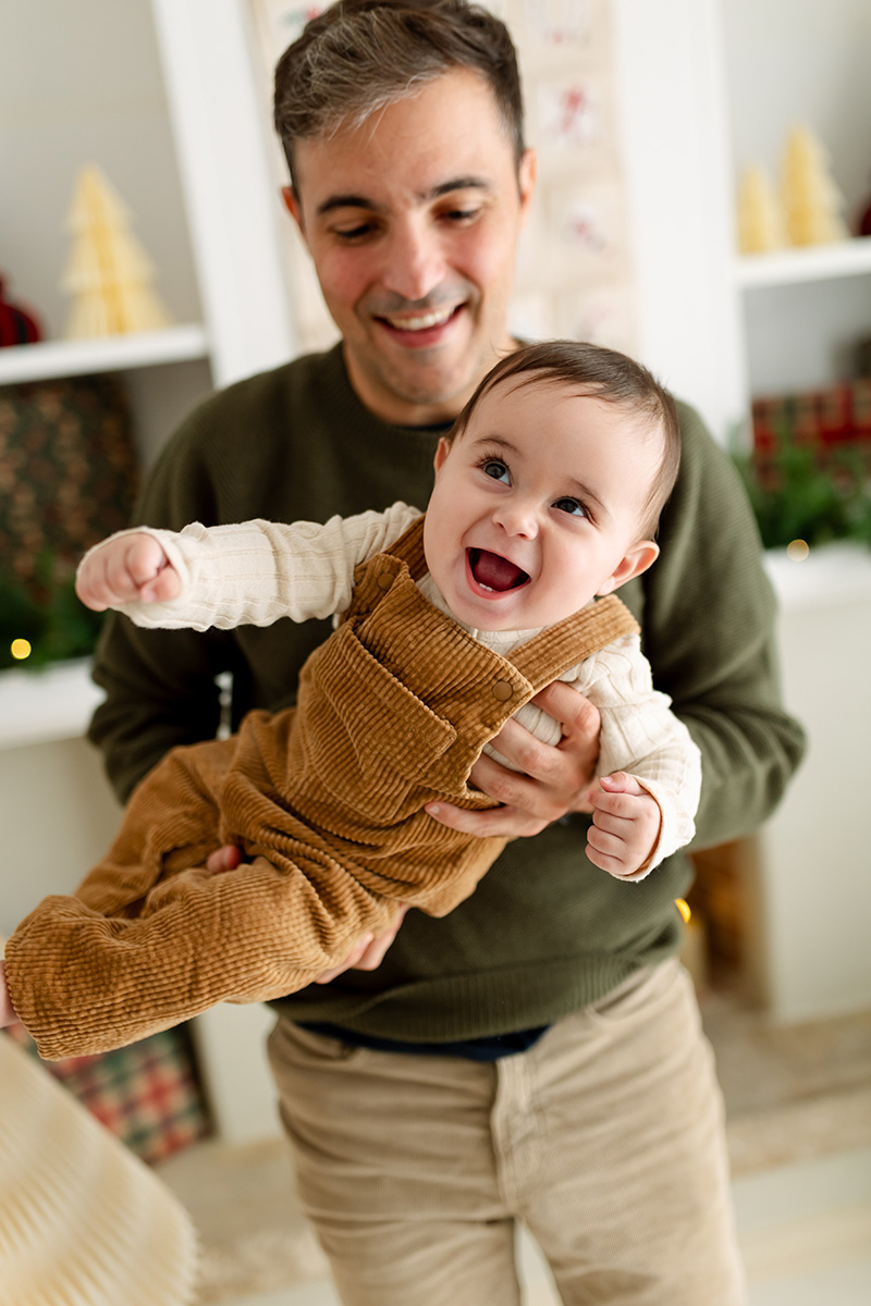 Papá jugando con su bebé con un decorado navideño de fondo