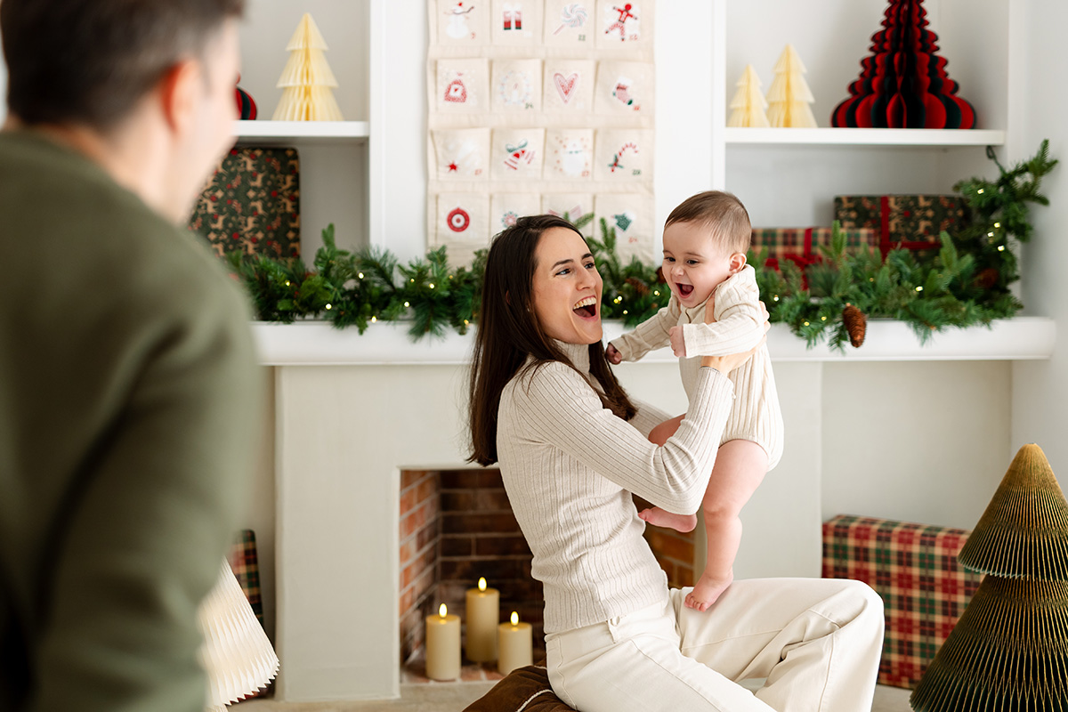 Mamá jugando con su bebé en escenario navideño minimalista
