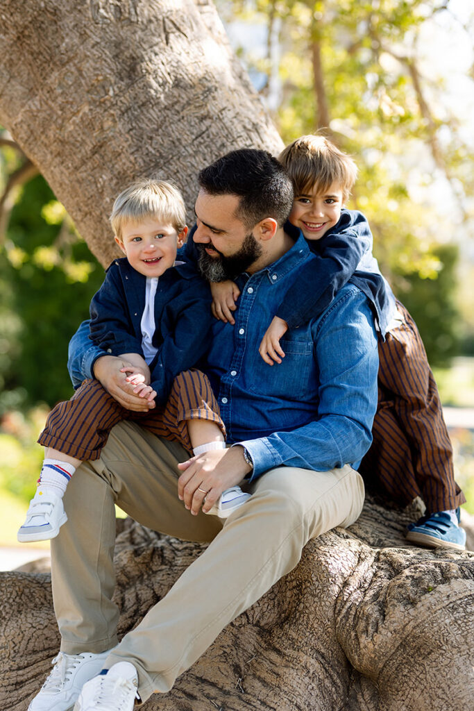 Padre con sus hijos jugando en un árbol de un parque de Barcelona