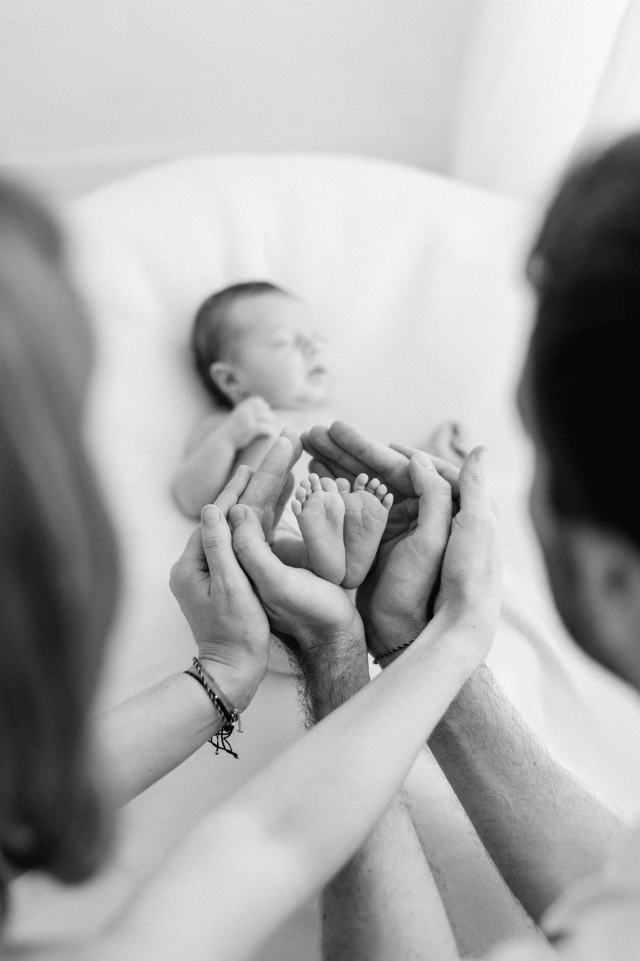 Padres sosteniendo los pies de su bebé recién nacido en una sesión newborn familiar natural en Barcelona, mostrando ternura y conexión.