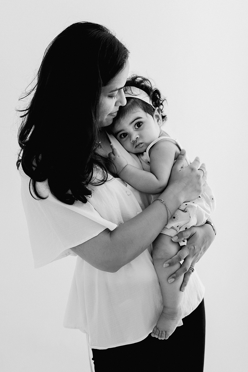 Mamá sosteniendo a su bebé de 8 meses durante sesión de fotos en estudio