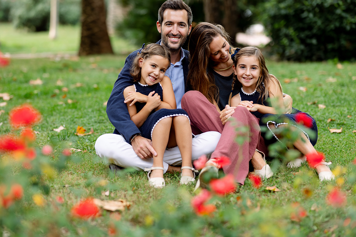 Familia sentada en un parque lleno de flores