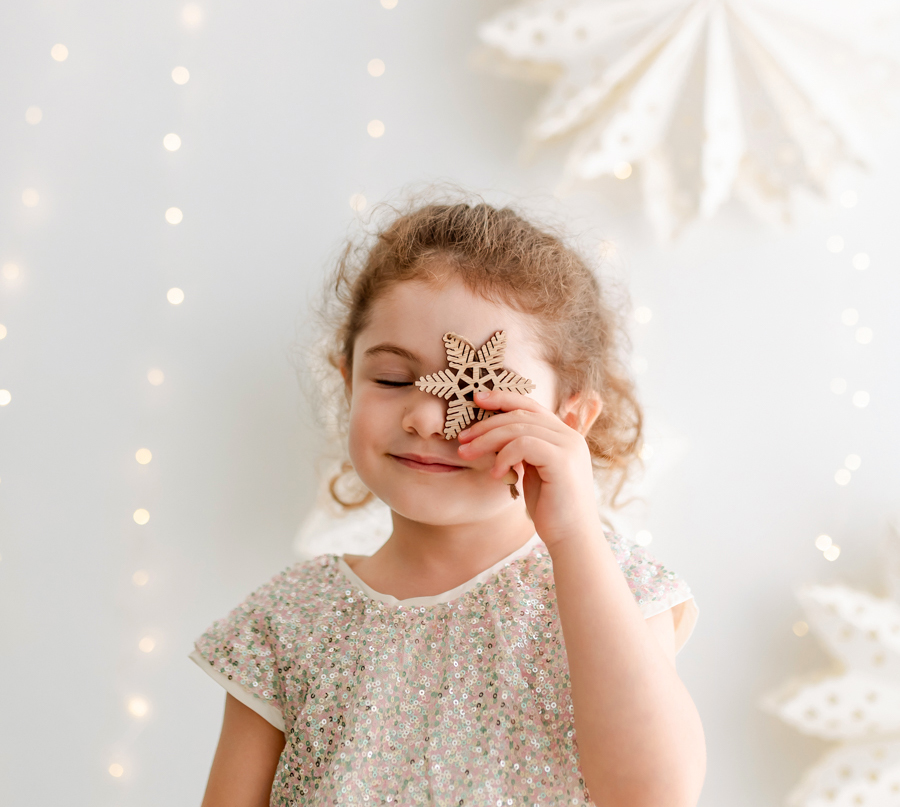niña cogiendo adorno de árbol y con estrellas y luces de navidad de fondo