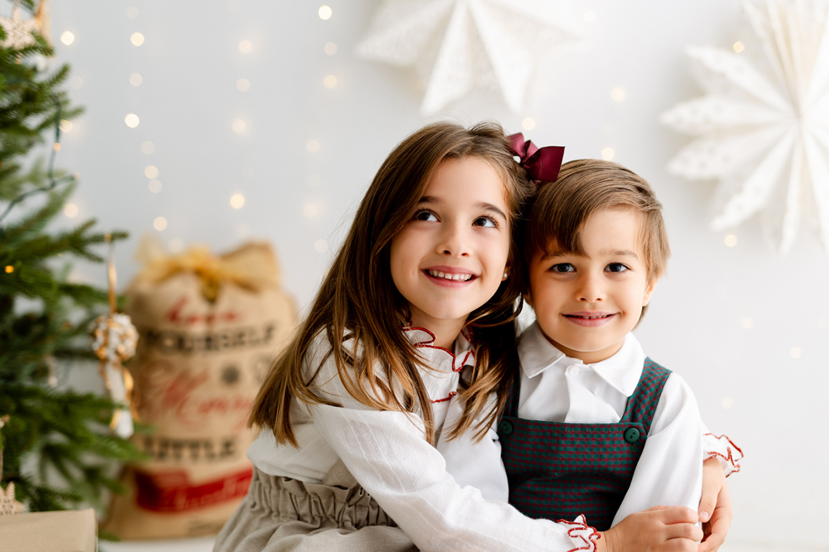 Hermanos abrazándose en sesión de fotos de Navidad en estudio en Barcelona